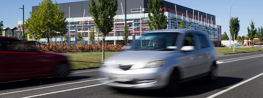 Image of a silver car driving past Glo Box Arena in Claudelands